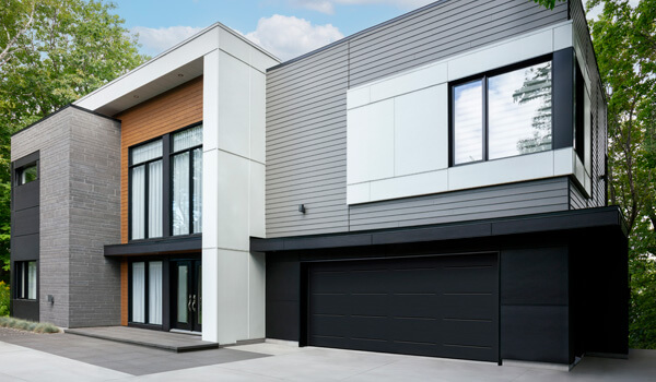Maison moderne, formes carrées, jouant les volumes et les textures, porte de garage double Vog Noir